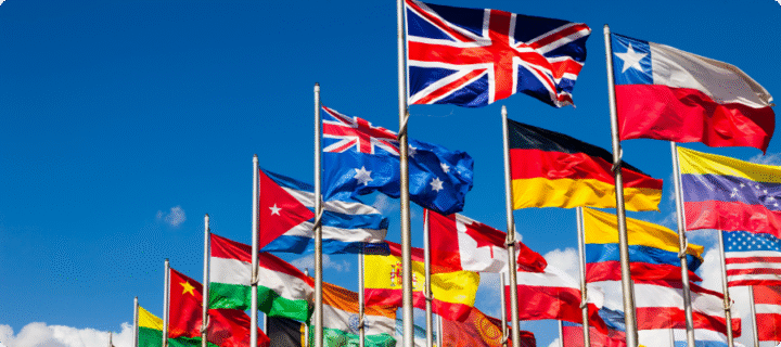 different country flags on poles, on a blue sky background